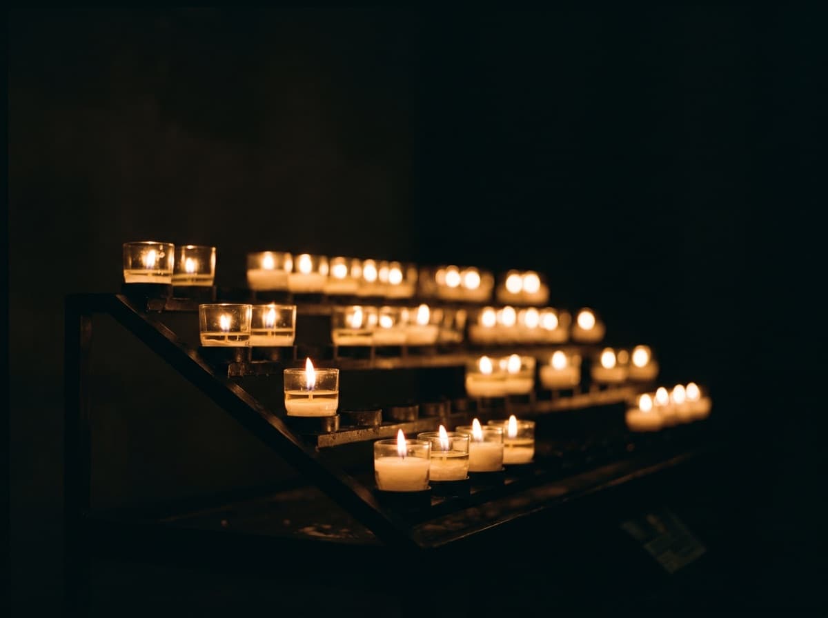 Rows of lit votive candles glowing in the dark
